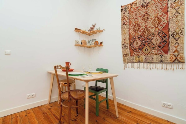 Un coin repas avec une table, des chaises et une tapisserie à motifs accrochée au mur.