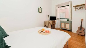 A bedroom with a bed, a table with a tray of food, a guitar, and a television. - Cosy 2 bed flat with terrace near Av Liberdade (Lisboa)