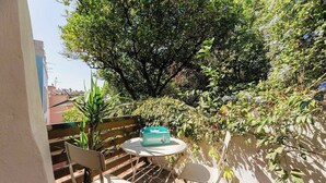 An outdoor seating area with a table and chairs, surrounded by lush greenery and a large tree. - Cosy 2 bed flat with terrace near Av Liberdade (Lisboa)