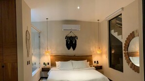 A bedroom with a large bed, two bedside tables, a hanging light fixture, and a mirror on the wall. - Penthouse Retreat w/Private Rooftop Pool (Tulum)