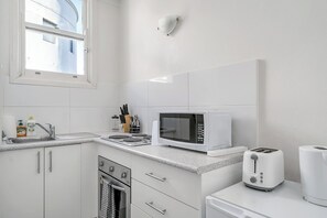 A modern kitchen with white cabinetry, a microwave, a toaster, and a sink. - Chic 1 BDR APT in the Heart of Manly (Manly)