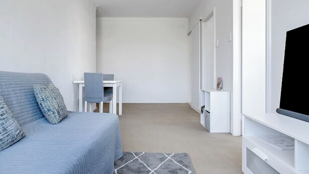 Een moderne, minimalistisch ingerichte kamer met een grijze bank, een kleine tafel en een televisie.