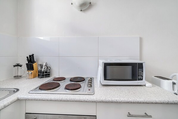 A kitchen with a microwave, a coffee maker, and a knife block.