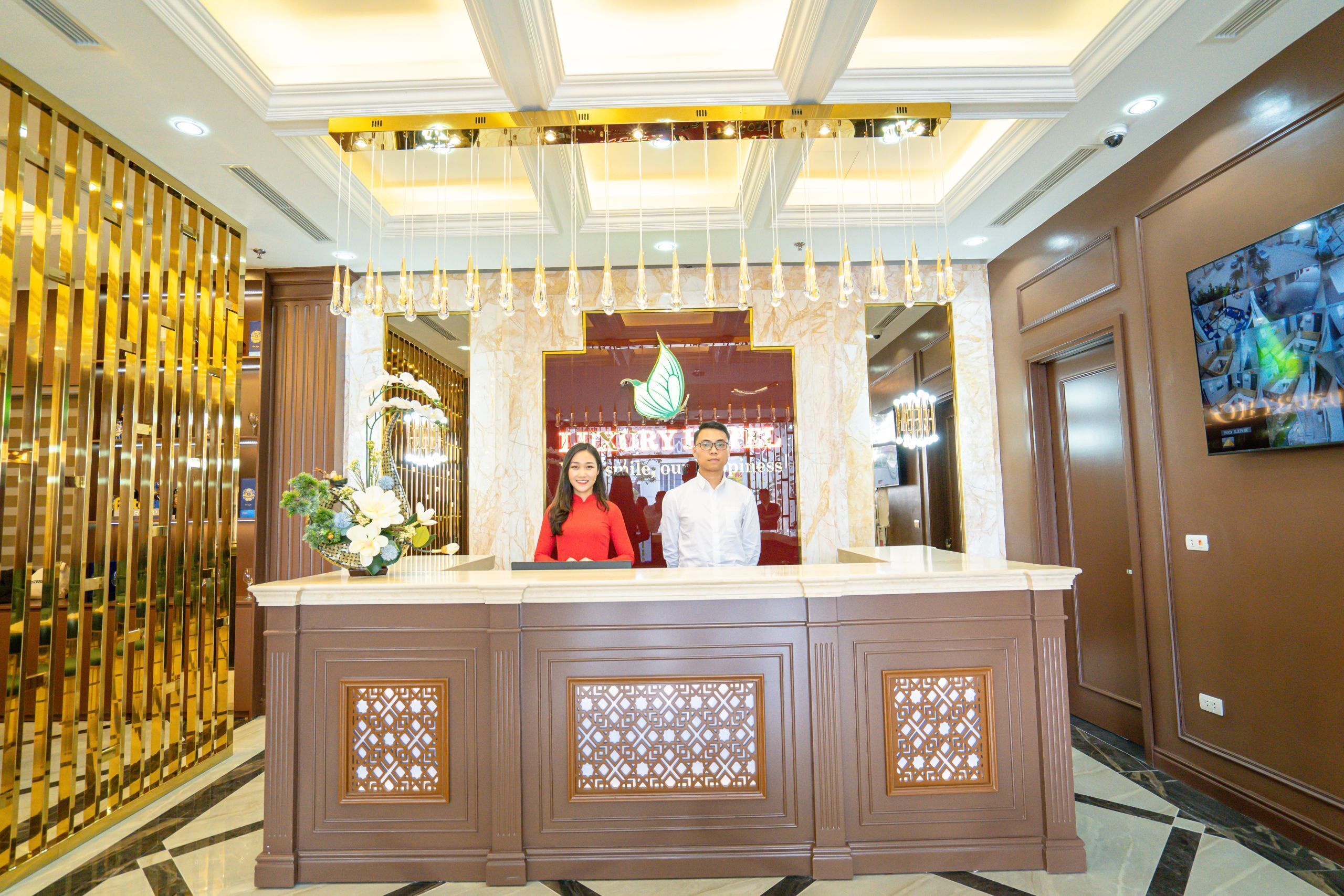 A reception desk with a decorative backdrop, a chandelier, and a framed artwork on the wall.