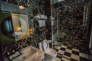 A bathroom with a checkered floor, a sink, a toilet, a shower, and a mirror with a circular frame. - Luxury Hotel (Van Giang)