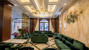 A spacious lobby with green sofas, a marble floor, and a large chandelier. - Luxury Hotel (Van Giang)