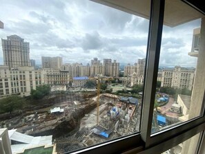Blick aus einem Fenster auf eine Baustelle mit Gebäuden im Hintergrund.