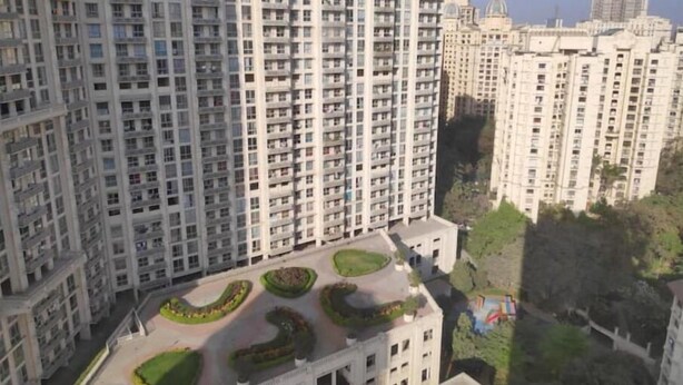 Um edifício residencial alto, com várias varandas e um terraço ajardinado.