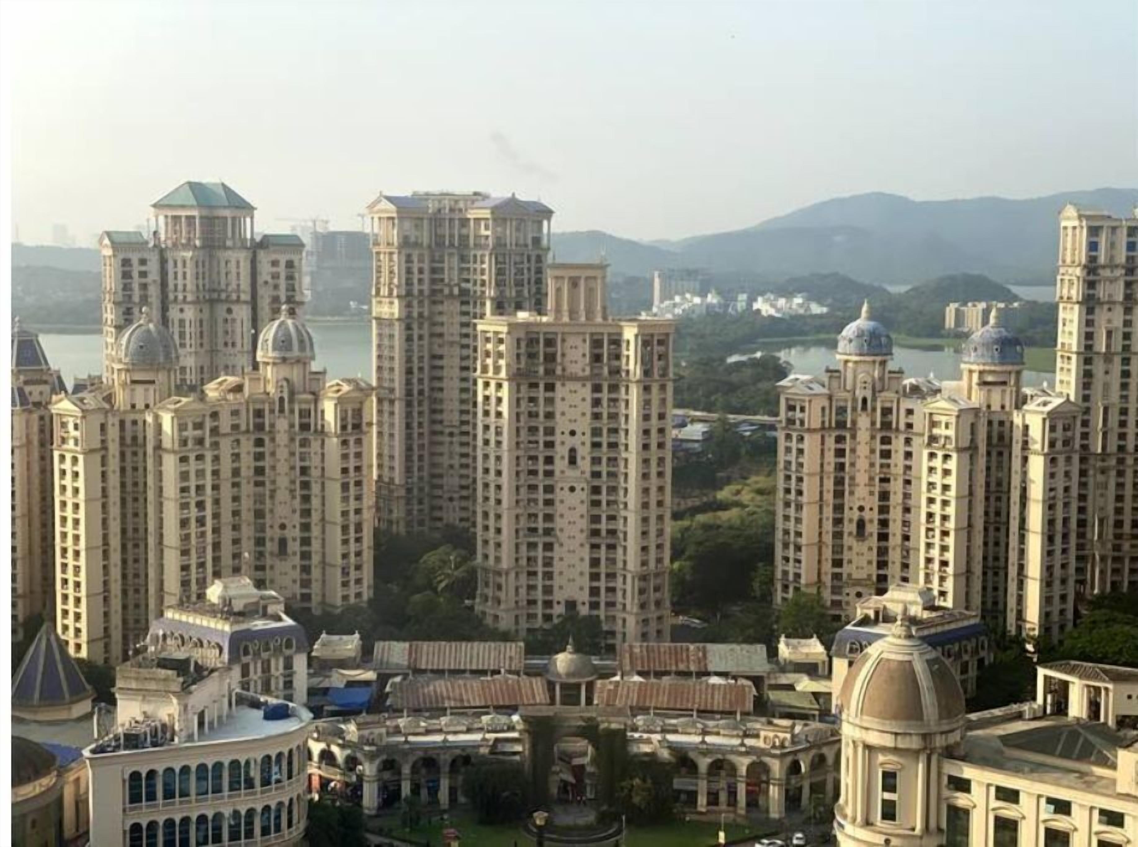 A high-rise residential building complex with multiple towers, some with domed roofs, and a central courtyard with a fountain.