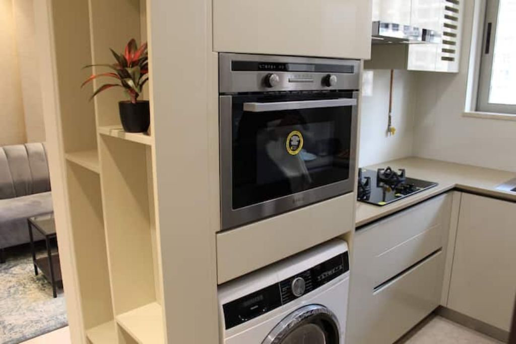 Uma cozinha compacta com forno embutido, micro-ondas e máquina de lavar.