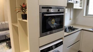 A compact kitchen with a built-in oven, microwave, and washing machine. - Luxurious budget stay in Powai (Ocean Heights)