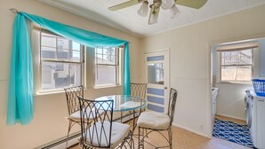 A room with a dining table and chairs, a ceiling fan, and a washing machine.