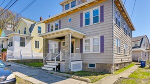 A two-story residential building with a porch, a garage, and a small front yard.