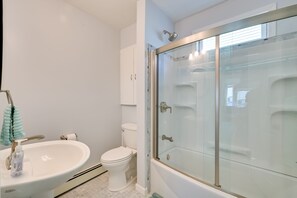 Uma casa de banho moderna com chuveiro em cabine de vidro, lavatório branco e sanita.