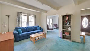 A living room with a blue sofa, wooden coffee table, and a bookshelf with decorative items.