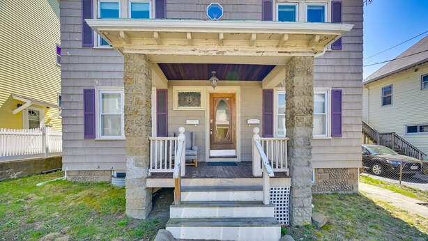 A two-story house with a front porch, stone pillars, and a small front yard.