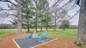 A seating area with two blue Adirondack chairs, a small table, and a fire pit.
