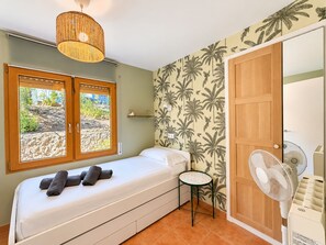Una camera da letto con un letto, due finestre, una ventola a muro e una porta.
