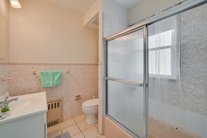 Une salle de bain équipée d’une douche, de toilettes, d’un lavabo et d’une serviette accrochée au mur.