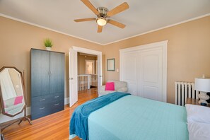 A bedroom with a bed, a wardrobe, a ceiling fan, a radiator, and a door leading to a balcony.