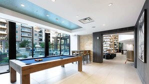 Uma área interna de piscina moderna, com mesa de bilhar, assentos e vista para a cidade.