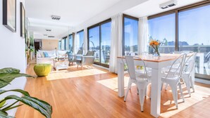 Ein modernes Wohnzimmer mit Essbereich, großen Fenstern und Blick auf die Stadt.