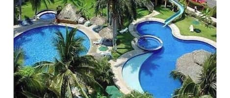 Relax by the serene pools surrounded by lush greenery and palm trees.