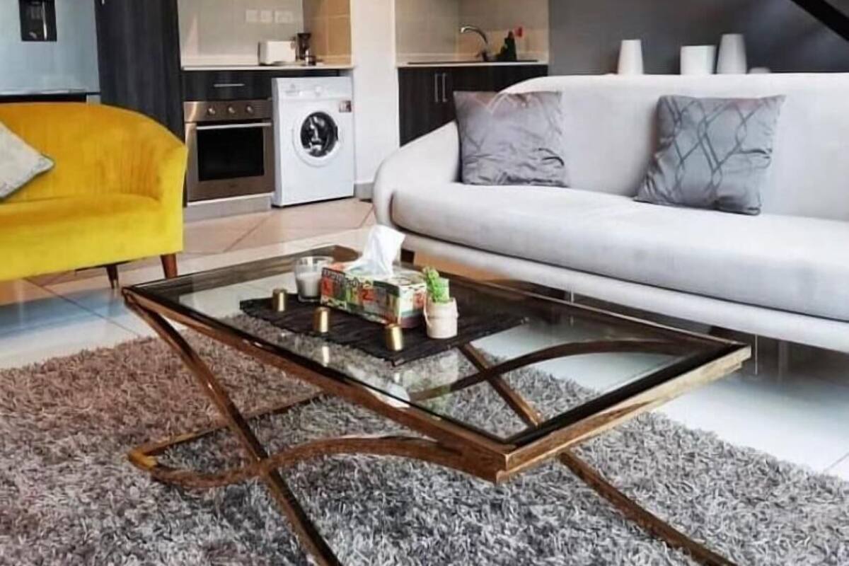 Una sala de estar moderna con un sofá, una mesa de centro y una cocina al fondo.