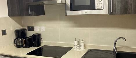 A compact kitchen with a microwave, oven, and washing machine.