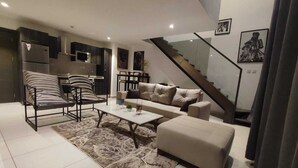 Una sala de estar moderna con un sofá, sillones, una mesa de centro y una escalera.