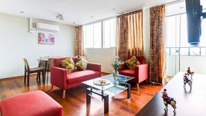 Una sala de estar moderna con un sofá rojo, una mesa de centro de vidrio y un comedor con una mesa y sillas.