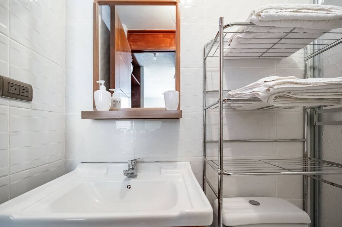 A bathroom with a white sink, a mirror, and a towel rack.