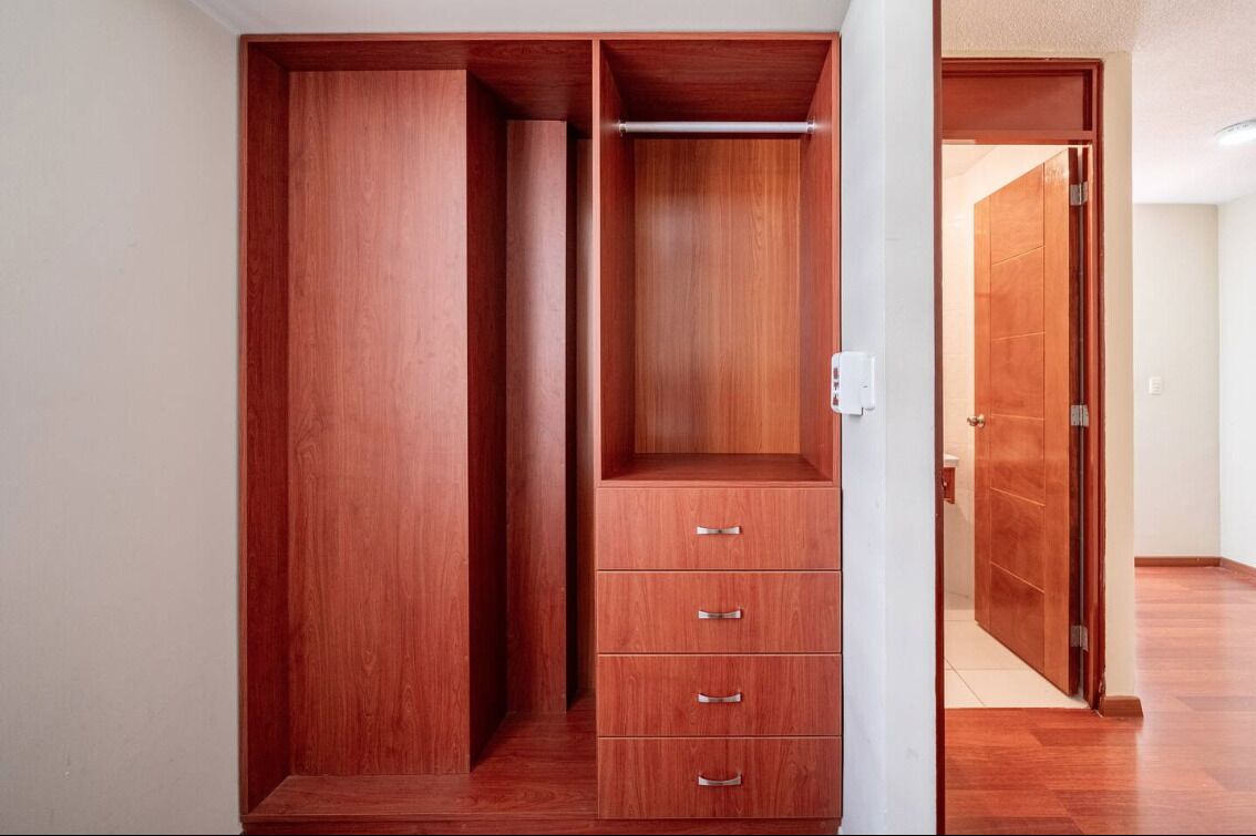 Un armario de madera con varios compartimentos y espacio para colgar.
