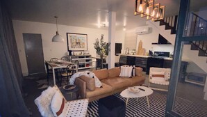 Een moderne woonkamer met een bank, een eettafel en een keuken in de achtergrond.