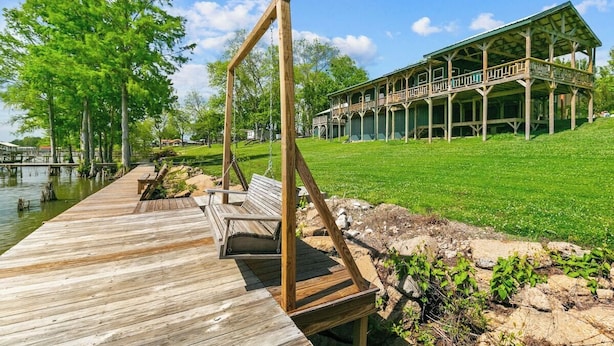 A wooden deck with a swing, a covered porch, and a building with a green roof.