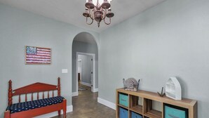 A room with a wooden bench, a wall-mounted American flag, a wooden console table with storage drawers, and a chandelier.