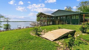 A lakeside property with a wooden deck, a covered outdoor area, and a view of the lake.