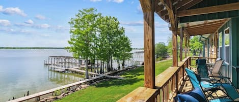 Terraza de madera con mobiliario exterior con vistas a un lago y un muelle.