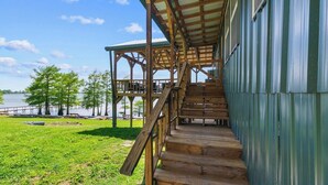 A wooden staircase leading to a covered outdoor area with a view of a body of water and trees.