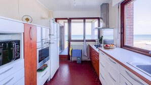Una cocina compacta con vista a la playa, un horno grande y un lavamanos.