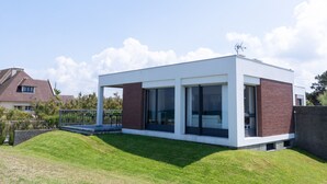 Una casa moderna con techo plano, ventanas amplias y fachada de ladrillo.