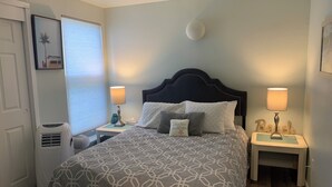 A neatly arranged bedroom with a large bed, two bedside tables with lamps, a wall-mounted light, and a framed picture on the wall.