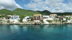 A coastal property with multiple buildings, including a large house with a balcony and a smaller structure with a red roof. - Villa at Playa Lagun Private Beach Curaçao (Curaçao)