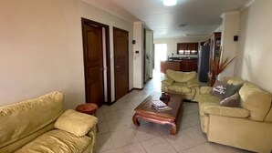 A living room with a sofa, a coffee table, and a kitchen in the background. - Villa at Playa Lagun Private Beach Curaçao (Curaçao)