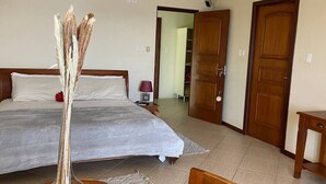 A bedroom with a large bed, a bedside table with a lamp, and a wooden wardrobe. - Villa at Playa Lagun Private Beach Curaçao (Curaçao)