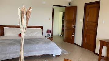 A bedroom with a large bed, a bedside table with a lamp, and a wooden wardrobe.