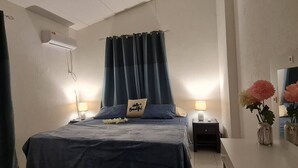 Une chambre à coucher avec un lit, des lampes de chevet, une table de chevet, un miroir et un vase avec des fleurs.