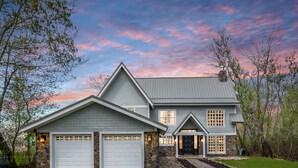 A two-story house with a stone foundation, a garage, and a well-maintained lawn.