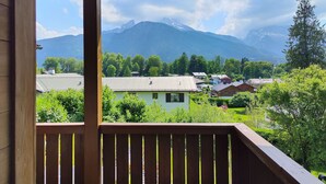 A balcony with a view of a mountain range and a village below.