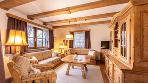 A cozy living room with wooden furniture, a sofa set, a coffee table, and a cabinet.